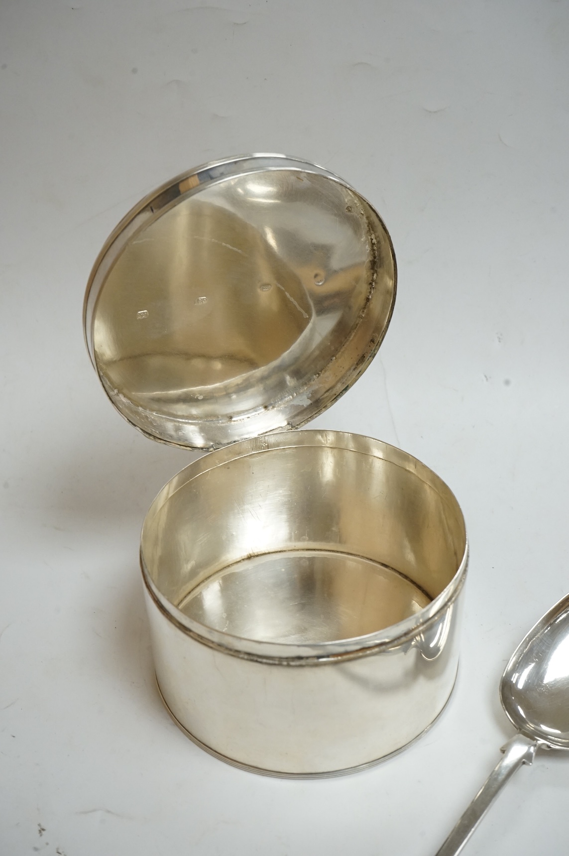 An early 19th century Dutch white metal circular biscuit box, with hinged cover and reeded bands, maker IT, retailed by Diemont, height 78mm, together with a pair of Victorian silver fiddle pattern table spoons by Willia